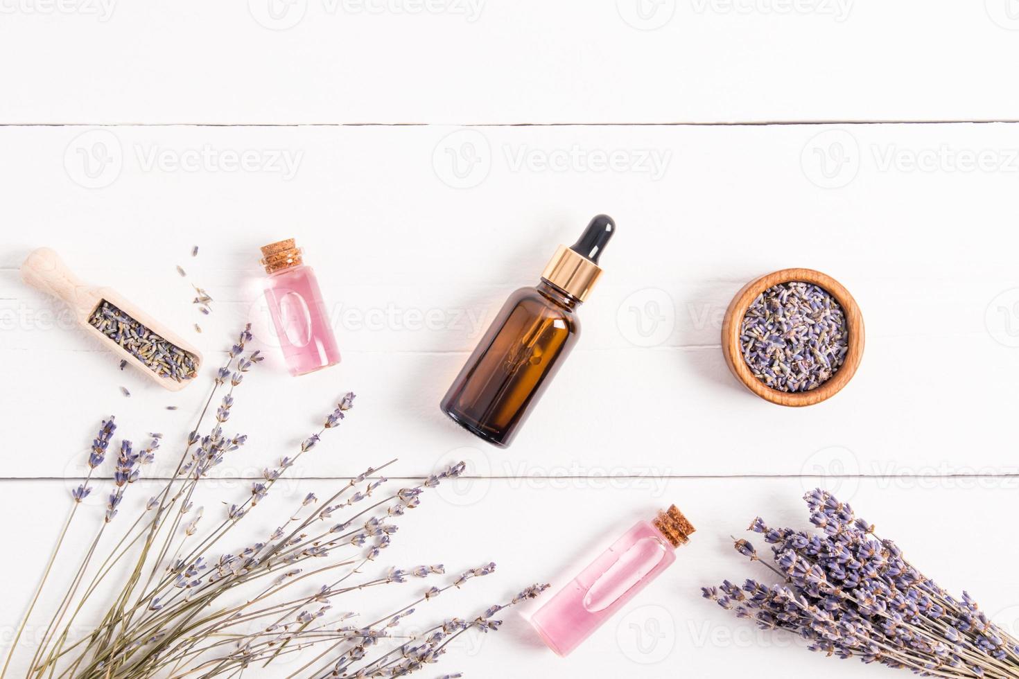 composition of natural cosmetic products in glass bottles, wooden bowl and scoop. top view. flat styling. white wooden background made of boards. photo