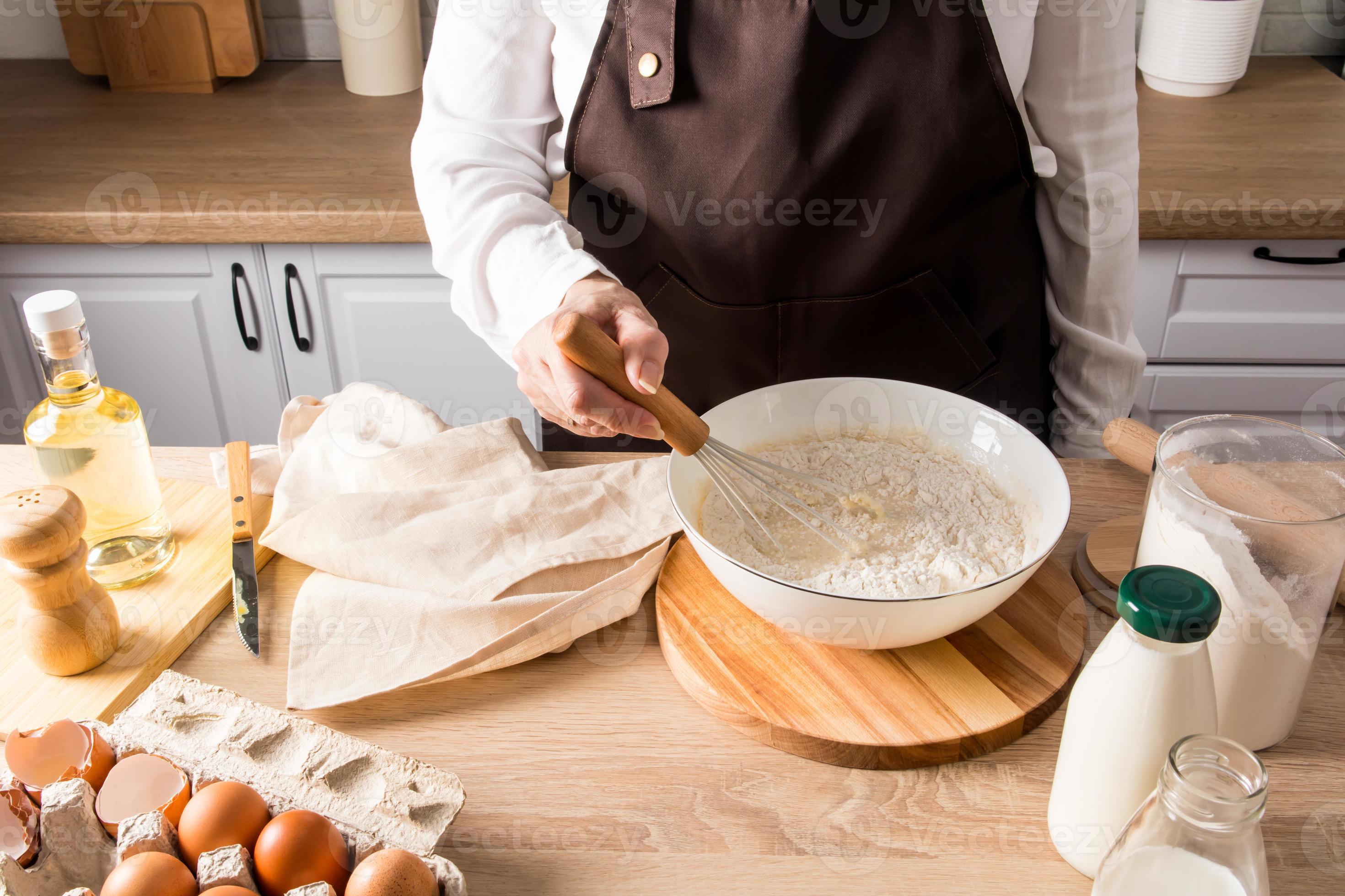 a woman's hand stirs the flour with a whisk in a bowl with the
