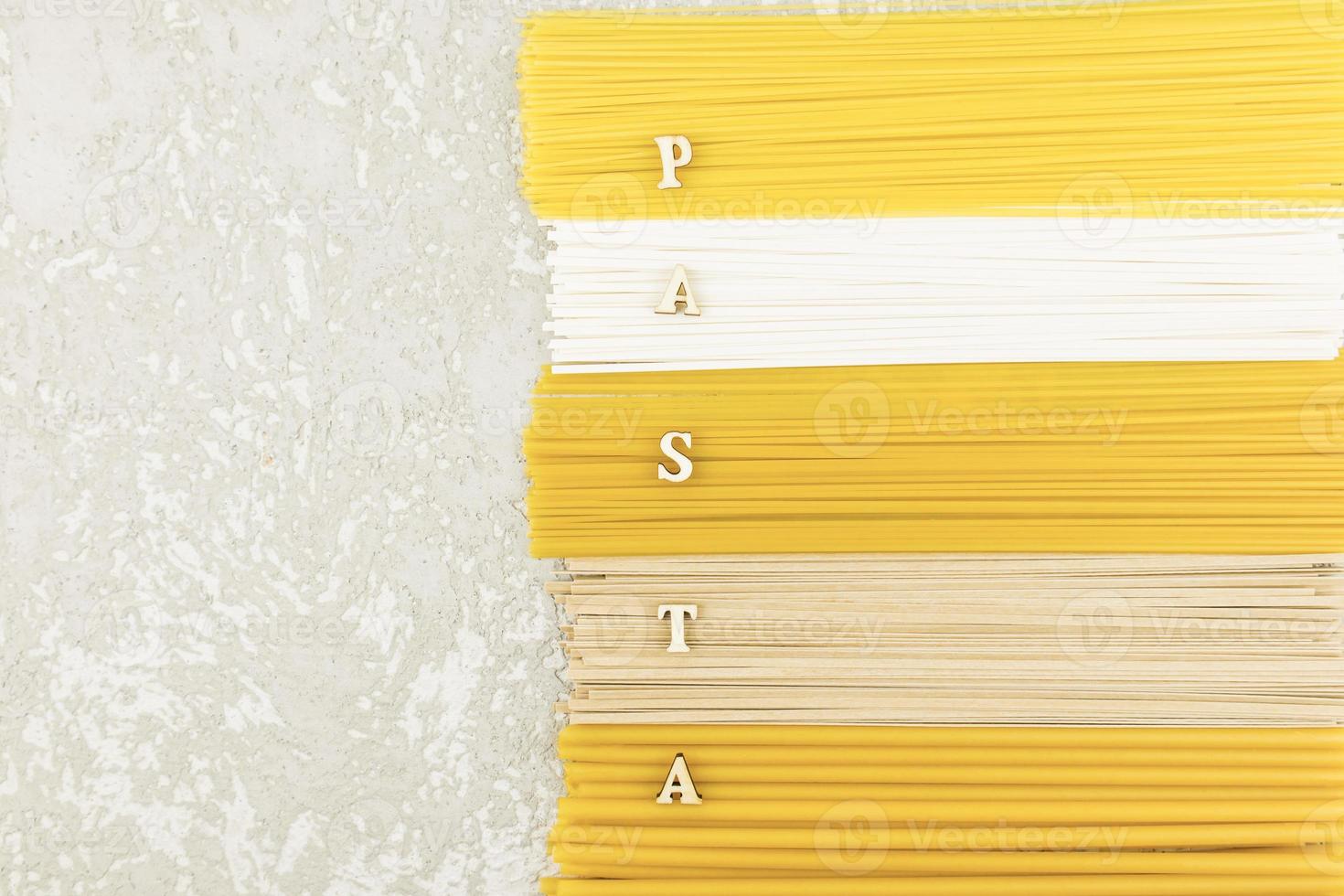 the top view of the dry Italian pasta, noodles, spaghetti on a gray background with a copy of the space and the letters of the word - pasta. flat lay. photo