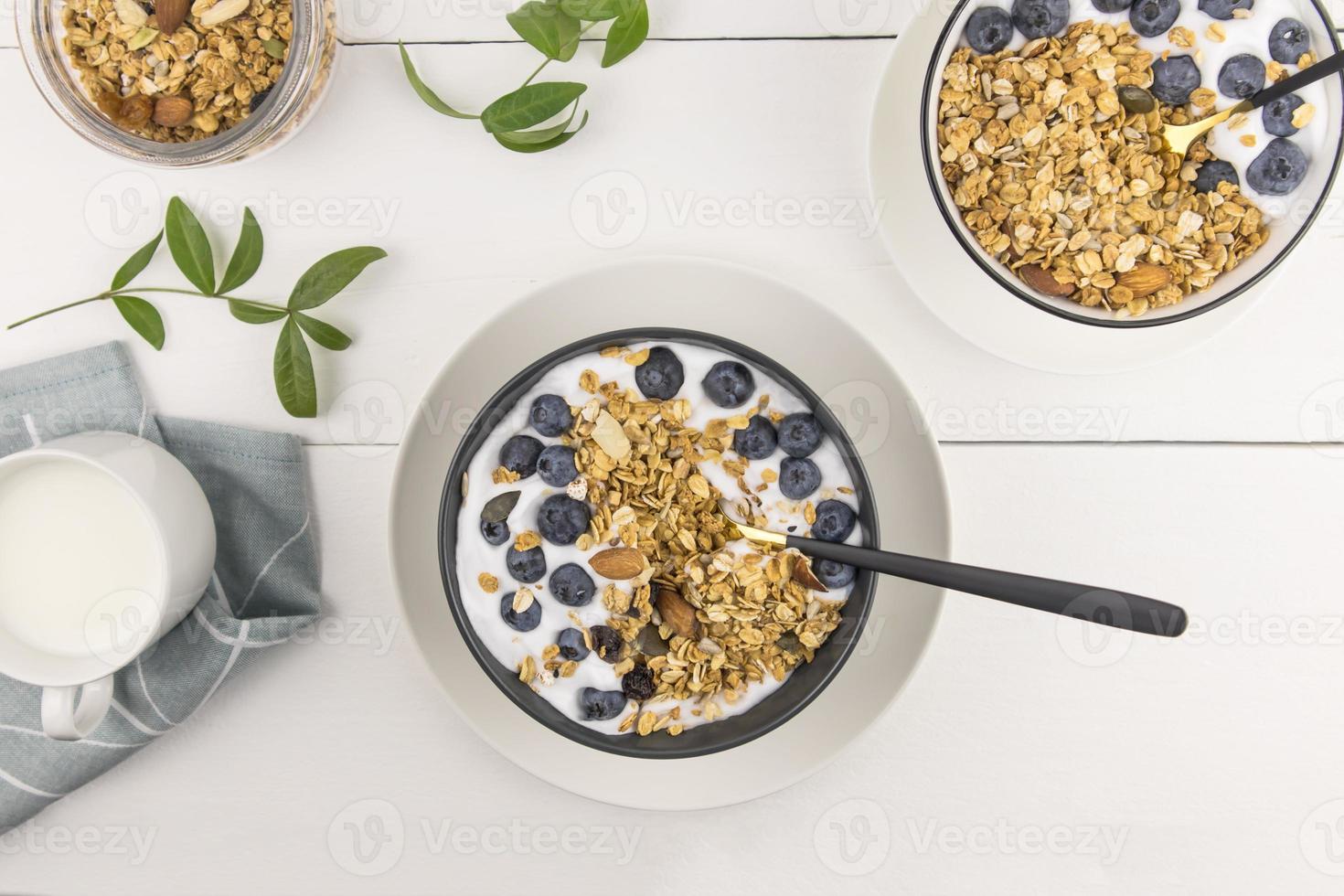 muesli casero o granola con leche en un bol de bayas maduras sobre una mesa de madera blanca. el concepto de alimentación saludable. foto