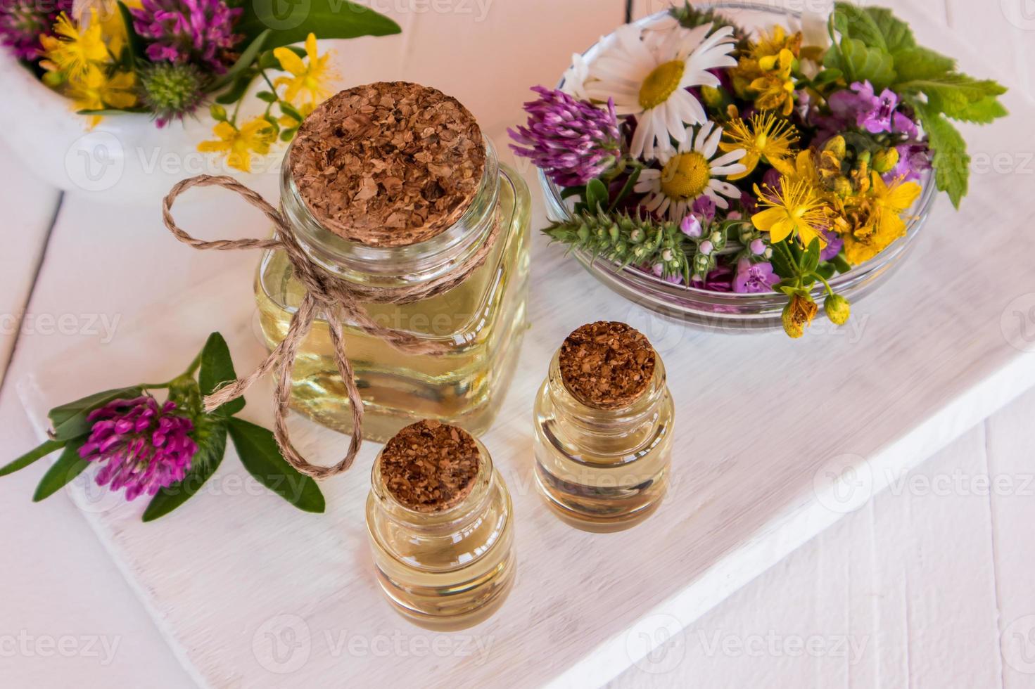 glass bottles with natural St. John's wort oil of white wooden boards and St. John's wort herb. an ideal remedy for problem skin of the face. photo