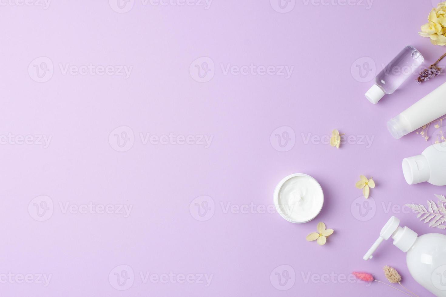 Cosmetic skin care products with flowers on rose background. Flat lay, copy space photo