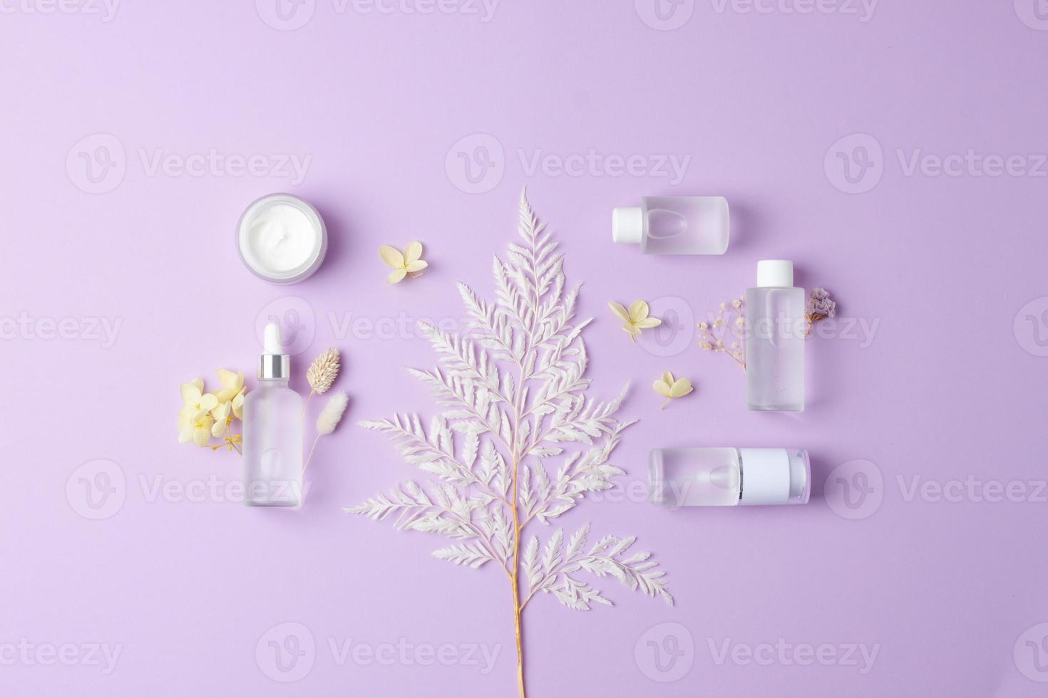 Cosmetic composition with cosmetic skin care products and flowers on rose background. Flat lay, copy space photo