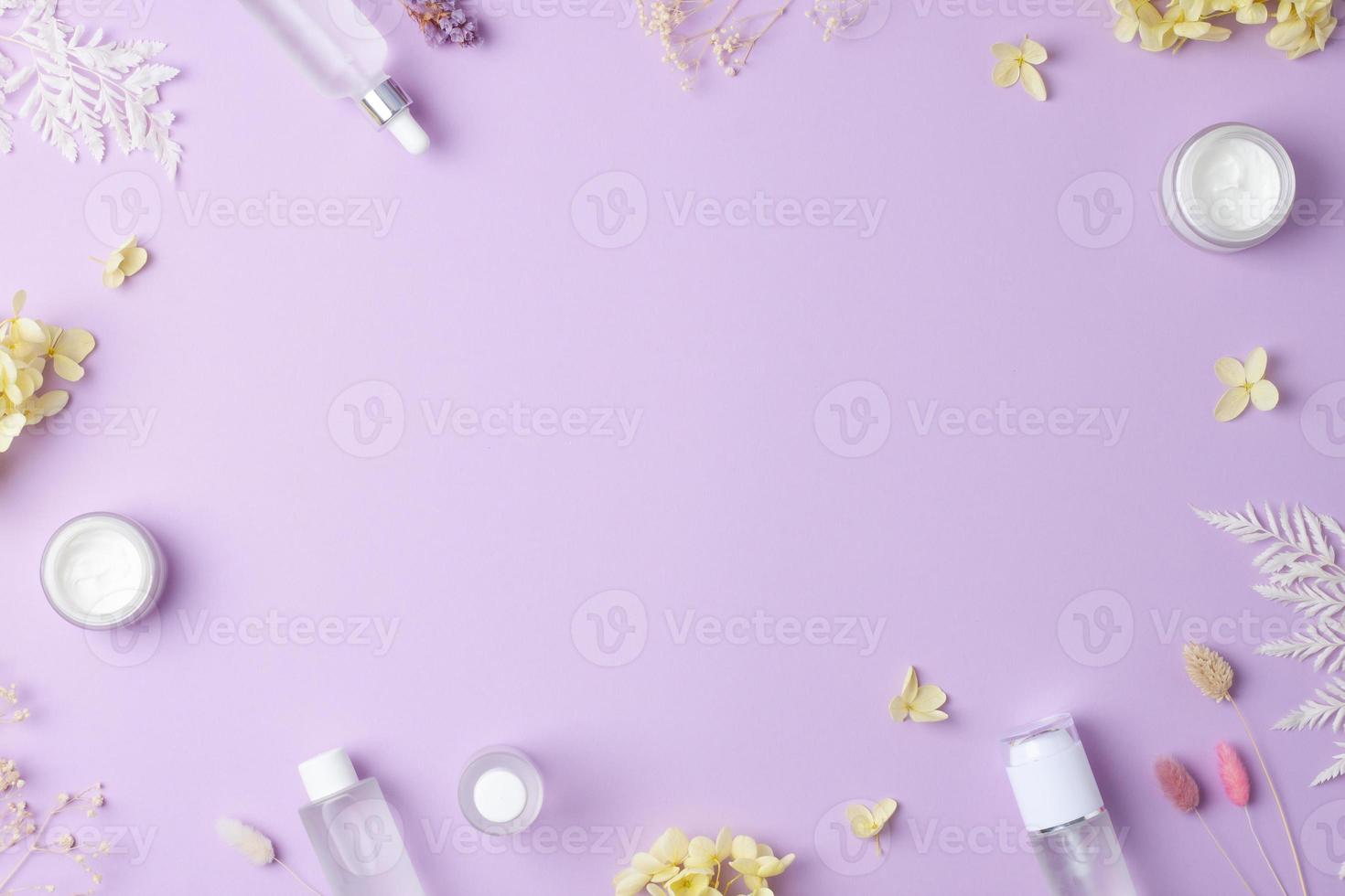 Cosmetic skin care products with flowers on rose background. Flat lay, copy space photo