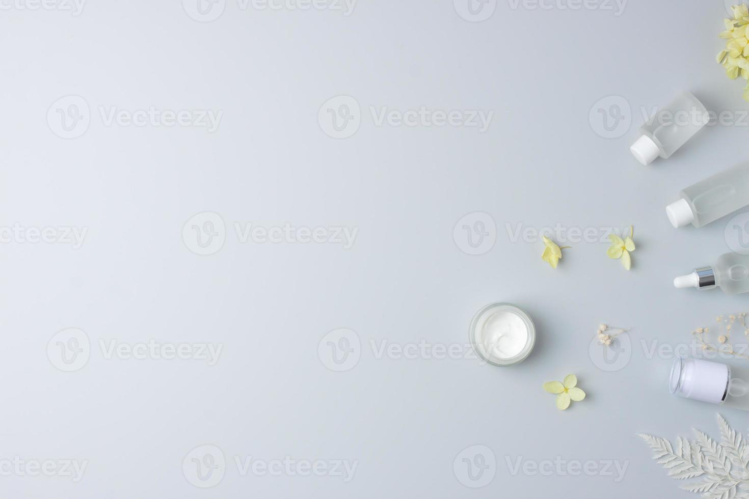 productos cosméticos para el cuidado de la piel con flores sobre fondo gris. endecha plana, espacio de copia foto