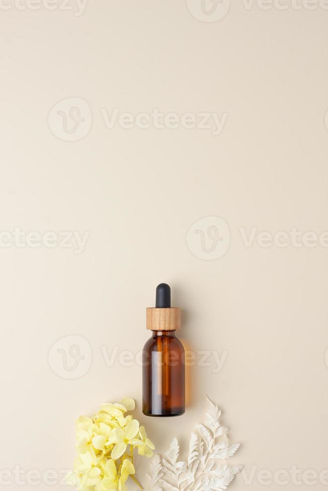 botella cosmética con flores sobre fondo beige pastel. endecha plana, espacio de copia foto