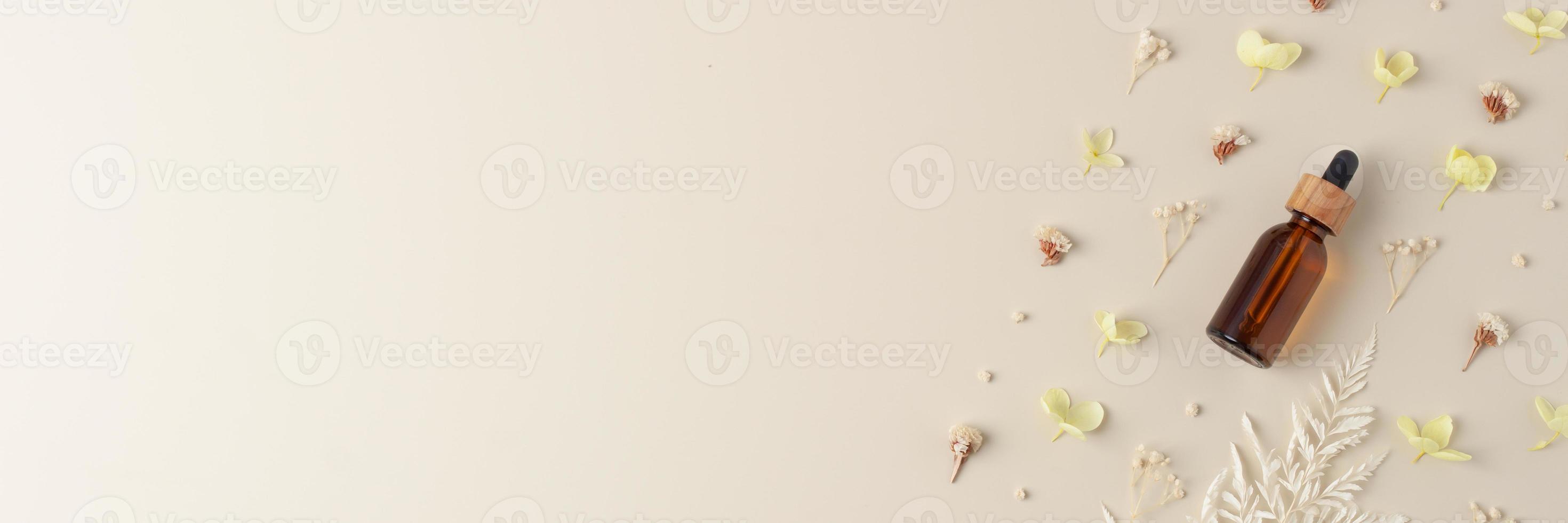 Cosmetic bottle with flowers on pastel beige background. Flat lay, copy space photo