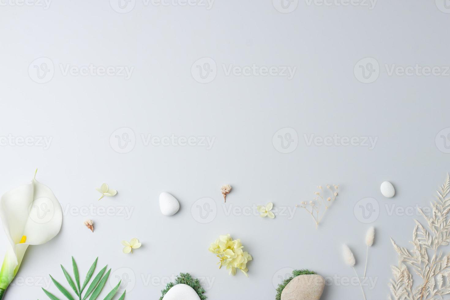 Cosmetic background with flowers, moss and stone on grey. Flat lay, copy space photo