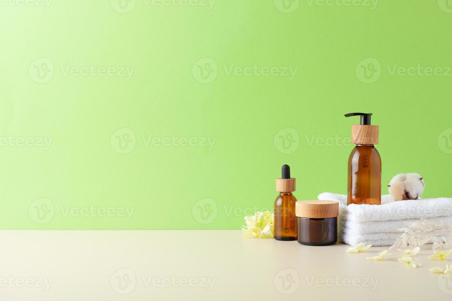 Spa treatment with natural skin care products, brush and flowers on green background. Close up, copy space photo