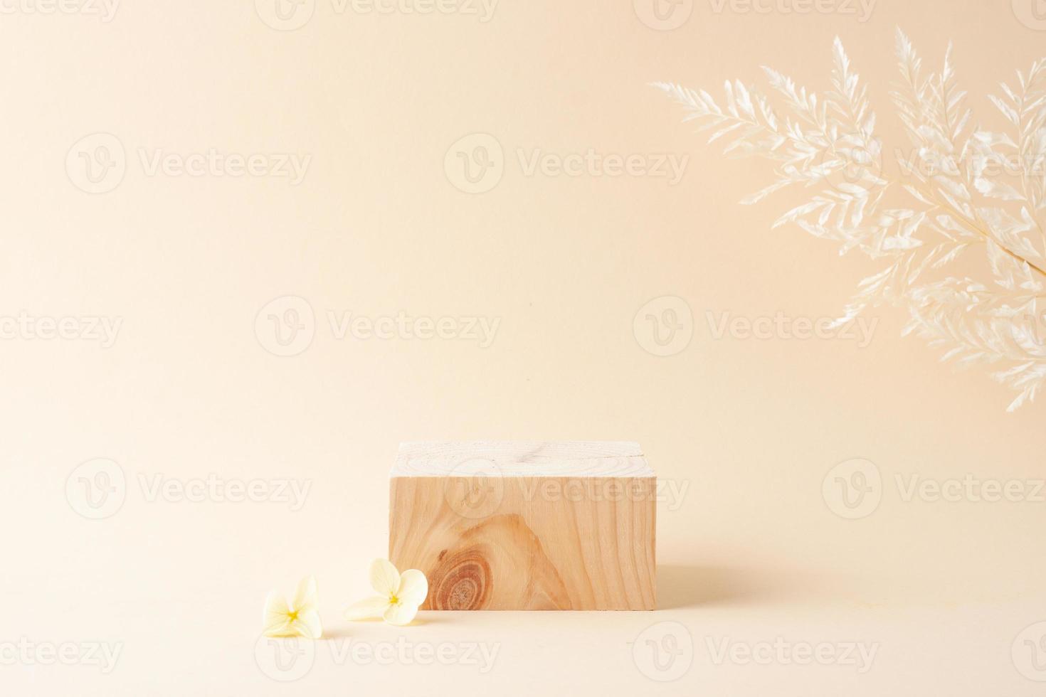 Cosmetic background with wood podium and flowers on pastel beige. Empty showcase for cosmetic product presentation on pastel beige background. Close up, copy space photo