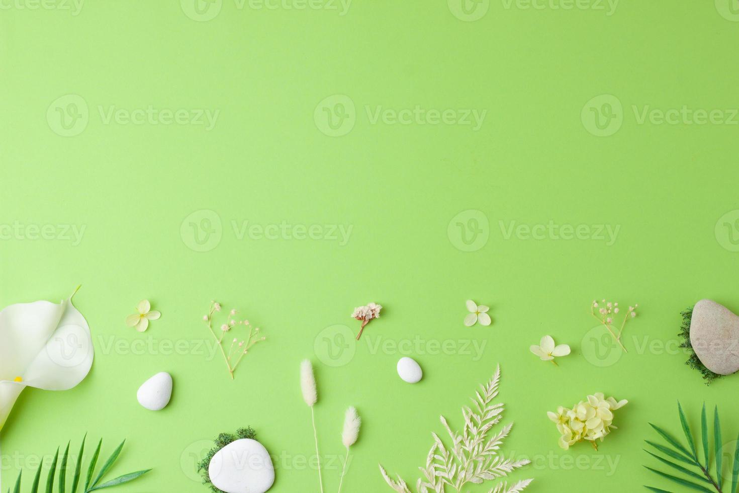 Cosmetic background with flowers, moss and stone on green. Flat lay, copy space photo