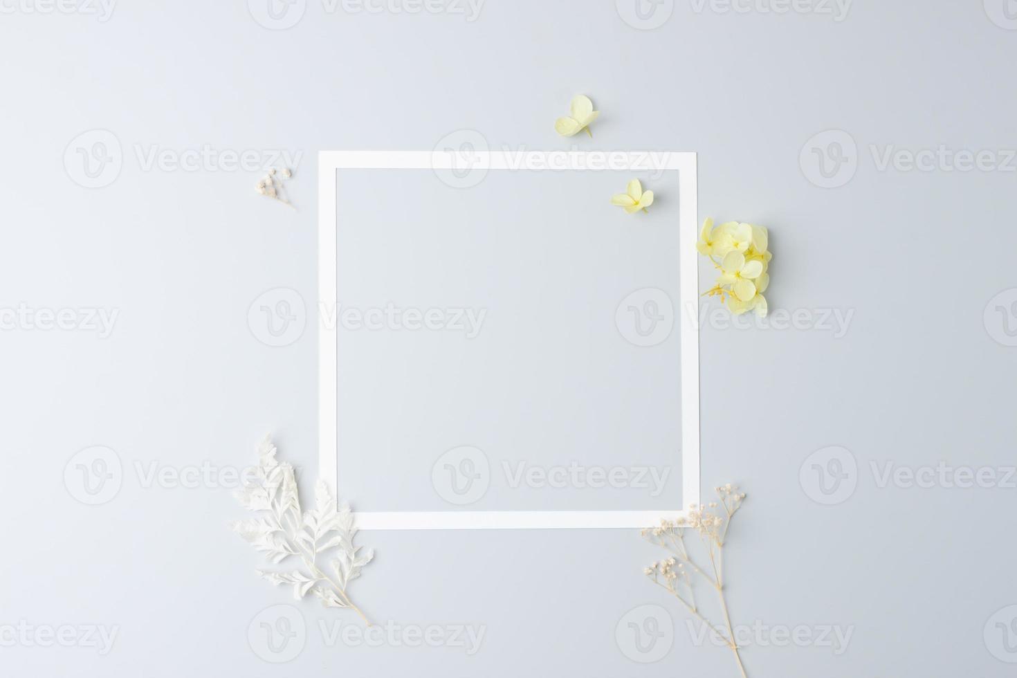 Cosmetic background with flowers and white frame on grey. Flat lay, copy space photo