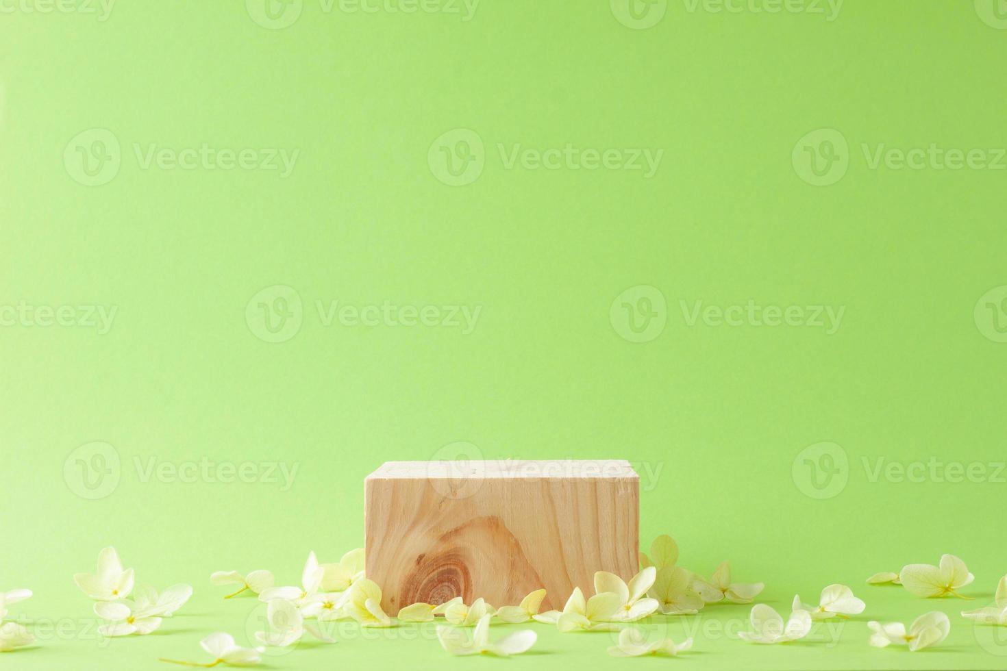 Cosmetic background with wood podium and flowers on green. Empty showcase for cosmetic product presentation. on green background. Close up, copy space photo