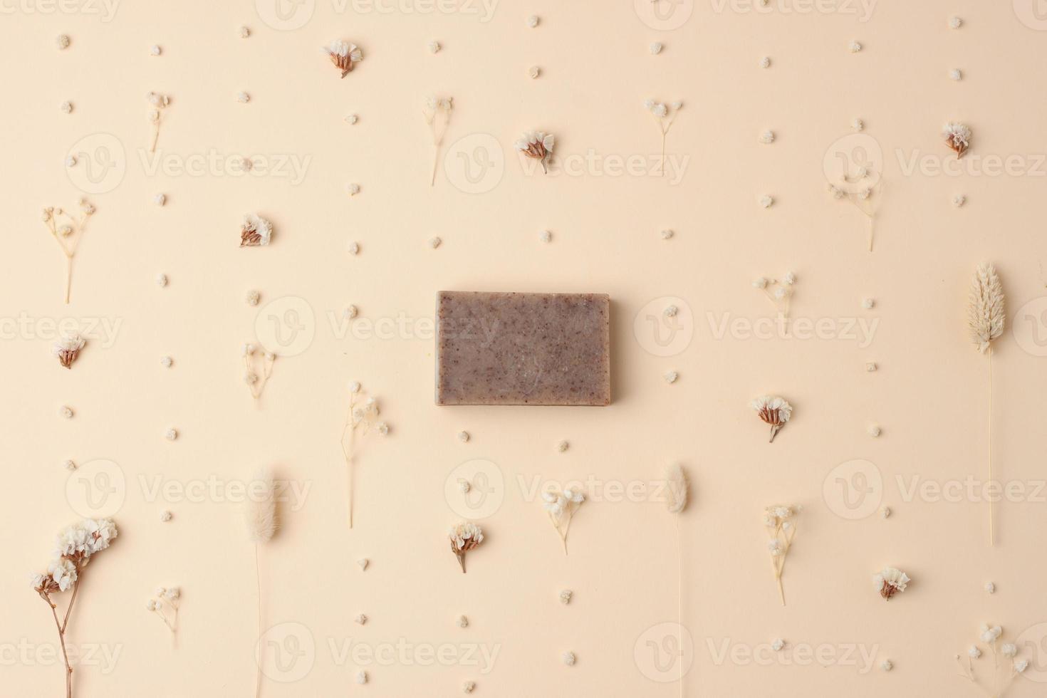 Soap and flower on beige background. Flat lay, copy space. photo