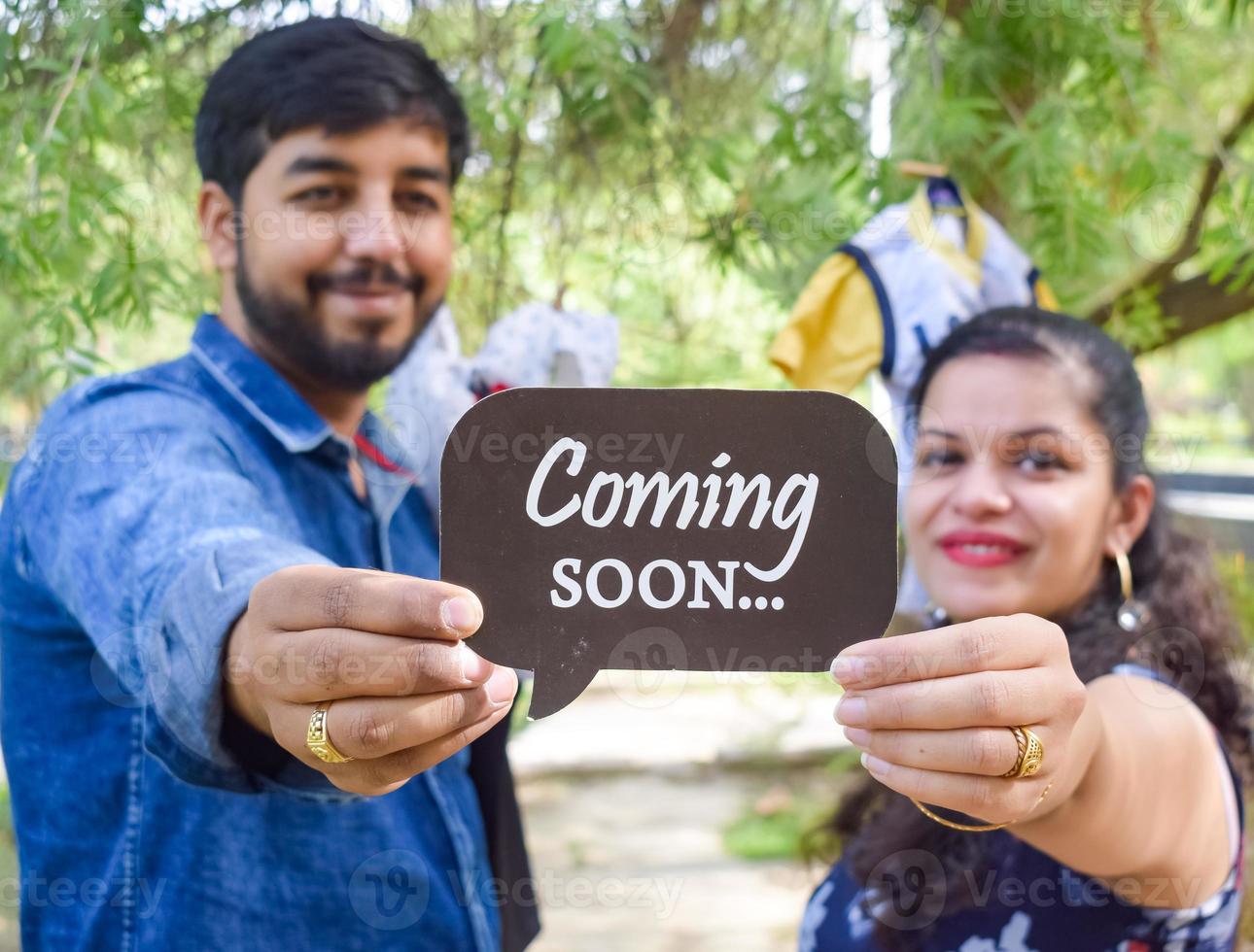 Indian couple posing for maternity baby shoot. The couple is posing in a lawn with green grass and the woman is falunting her baby bump in Lodhi Garden in New Delhi, India photo