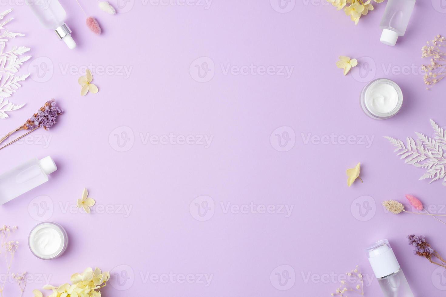 Cosmetic skin care products with flowers on rose background. Flat lay, copy space photo