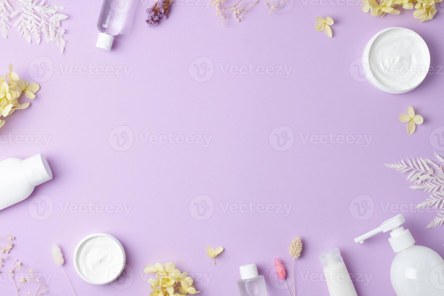 Cosmetic skin care products with flowers on rose background. Flat lay, copy space photo