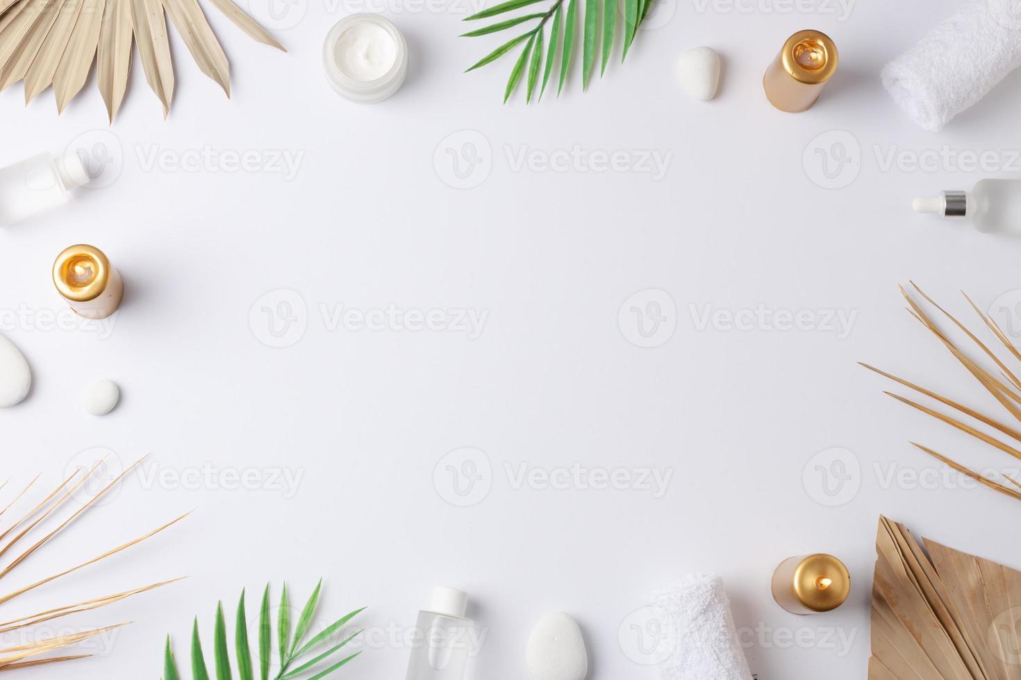 Spa treatment with cosmetic bottle, candles and palm leaf on white background. Flat lay, copy space photo