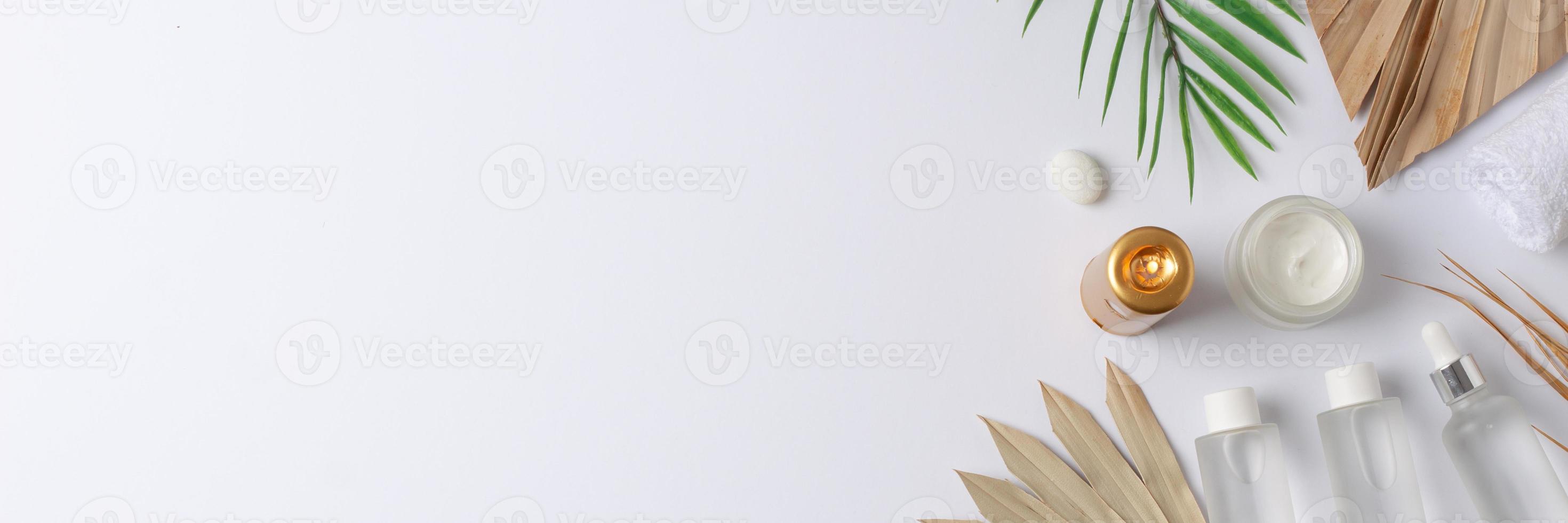 Spa treatment with cosmetic bottle, candles and palm leaf on white background. Flat lay, copy space photo