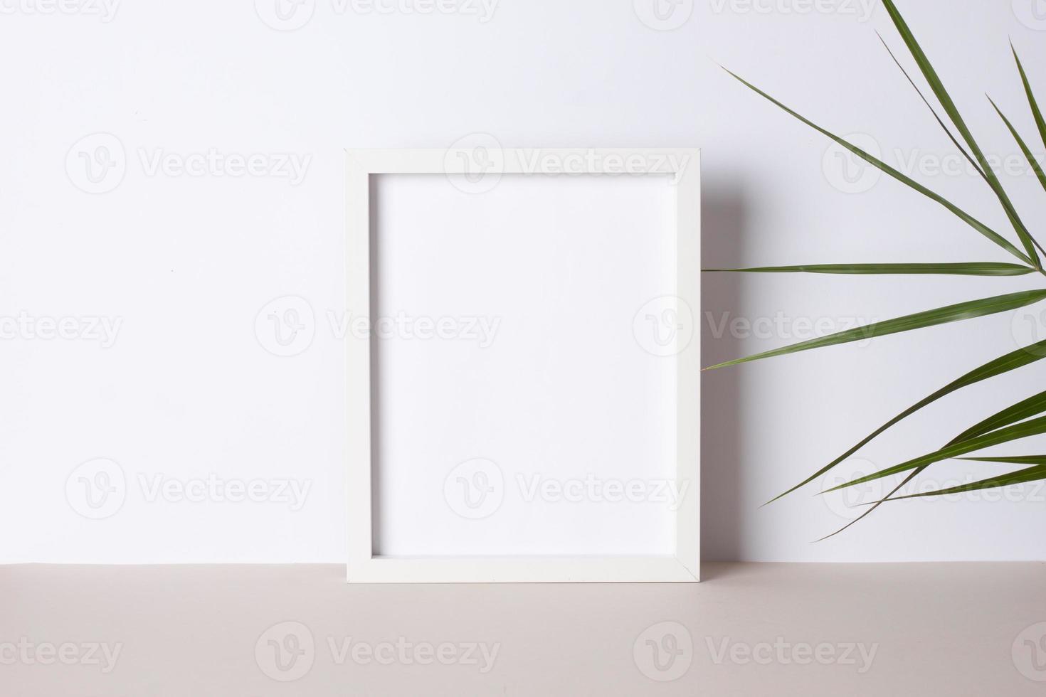 Home decoration with white mock up frame and palm leaf on grey. Artwork showcase. Close up, copy space photo