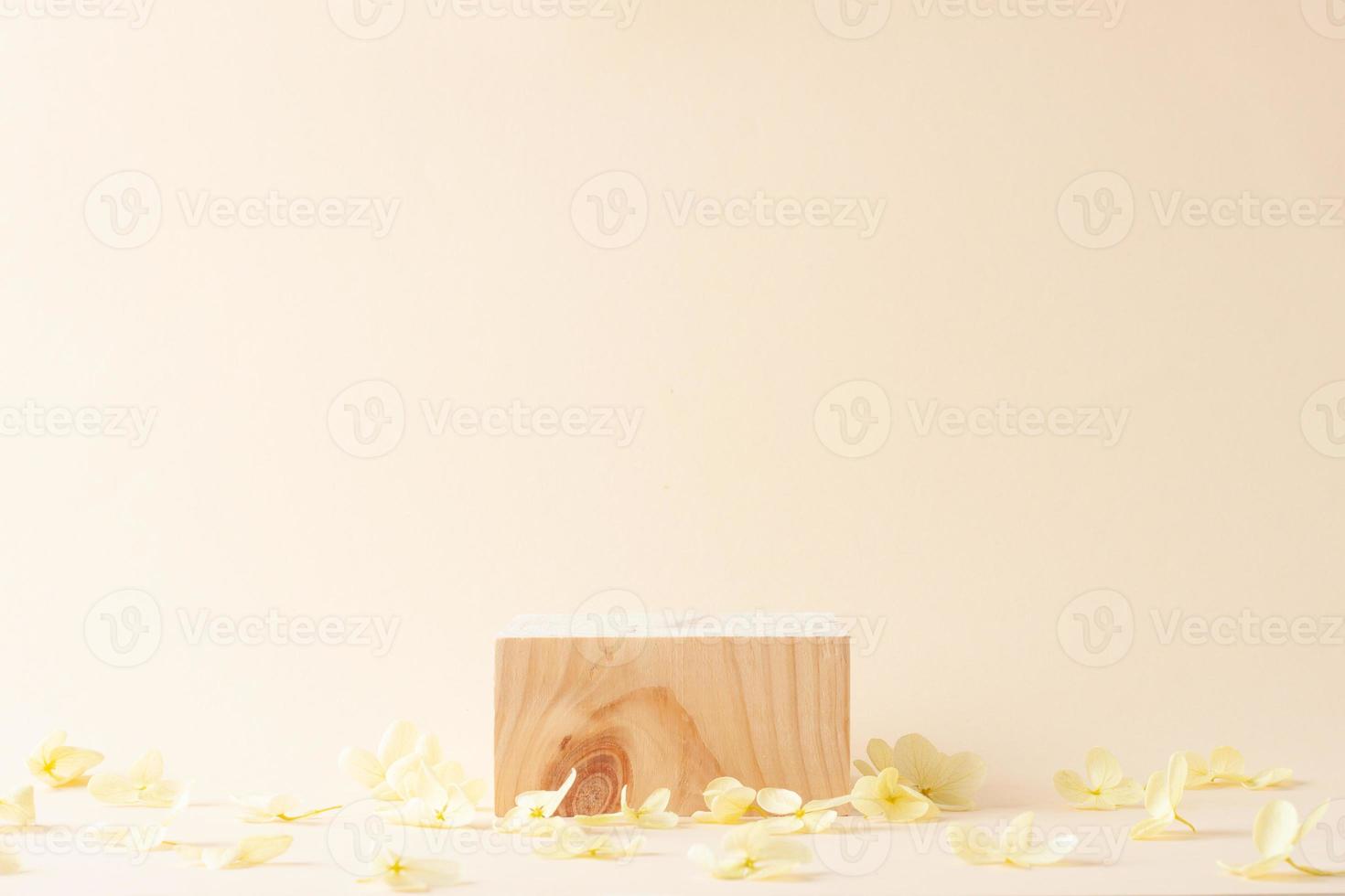 Cosmetic background with wood podium and flowers on pastel beige. Empty showcase for cosmetic product presentation on pastel beige background. Close up, copy space photo