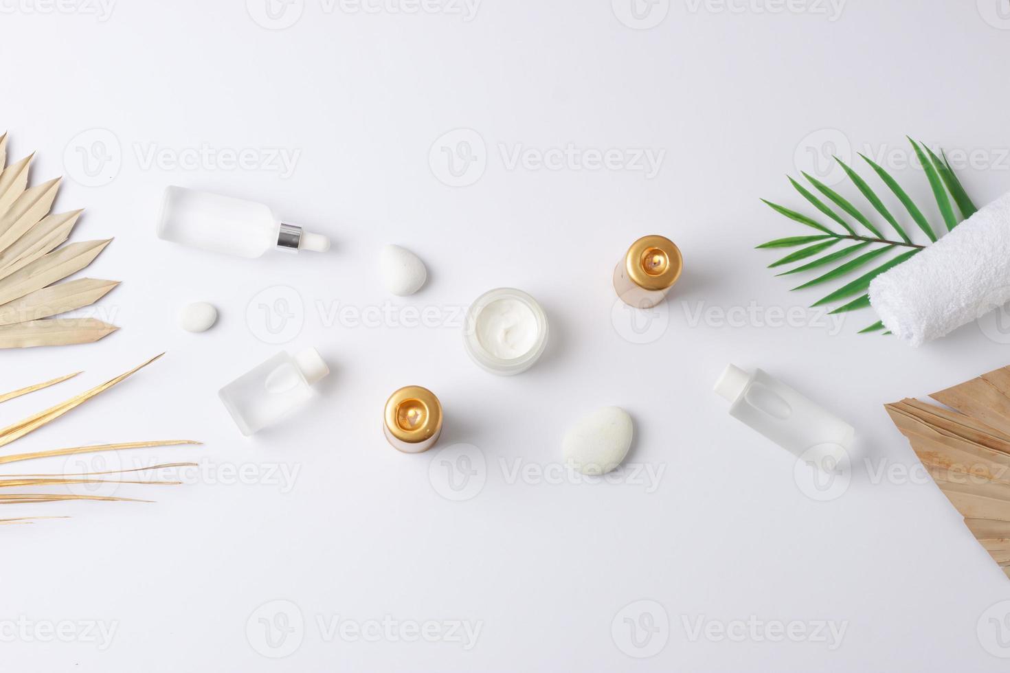 Spa treatment with cosmetic bottle, candles and palm leaf on white background. Flat lay, copy space photo