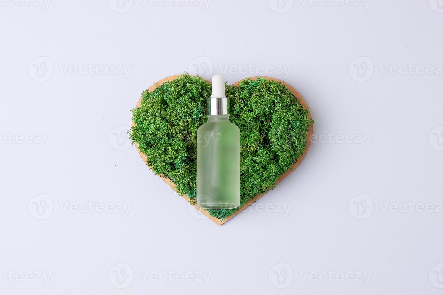 Cosmetic bottle with a wooden heart and moss on white background. Flat lay, copy space photo