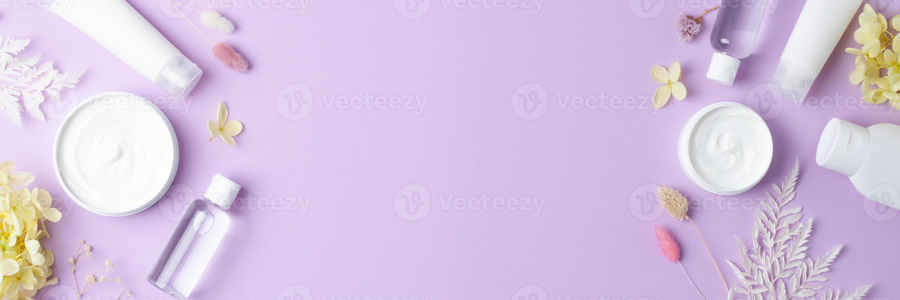 Cosmetic skin care products with flowers on rose background. Flat lay, copy space photo