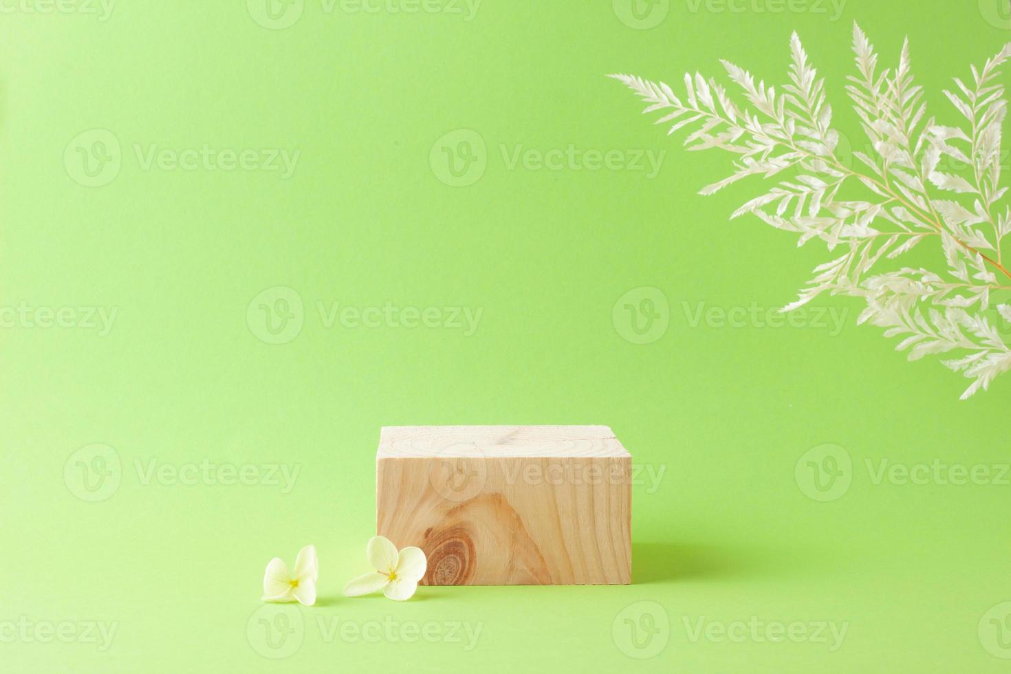 Cosmetic background with wood podium and flowers on green. Empty showcase for cosmetic product presentation. on green background. Close up, copy space photo