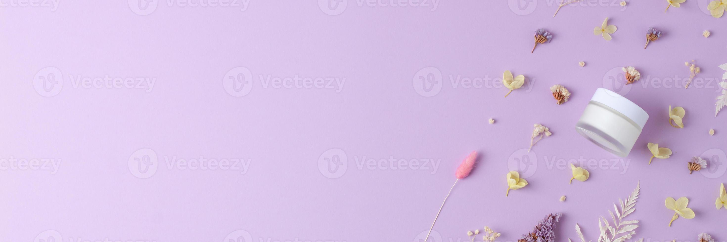 Jar of cosmetic cream with flowers on rose background. Flat lay, copy space photo