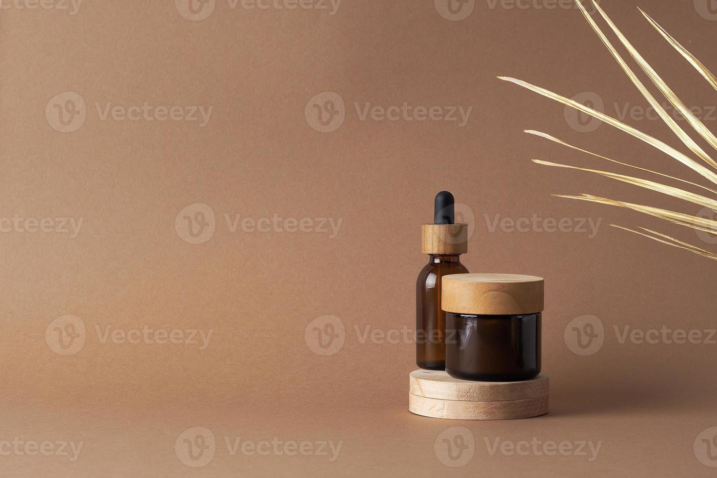 Cosmetic skin care products with wood podium and palm leaf on brown background. Close up, copy space photo