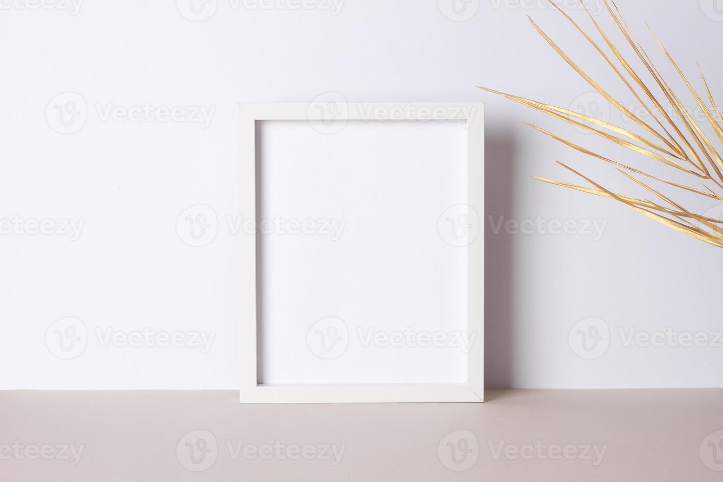 Home decoration with white mock up frame and palm leaf on grey. Artwork showcase. Close up, copy space photo