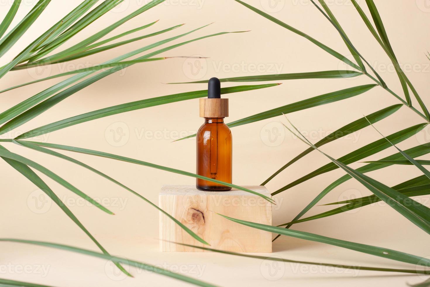 Cosmetic bottle with wood podium and palm leaf on pastel beige background. Close up, copy space photo