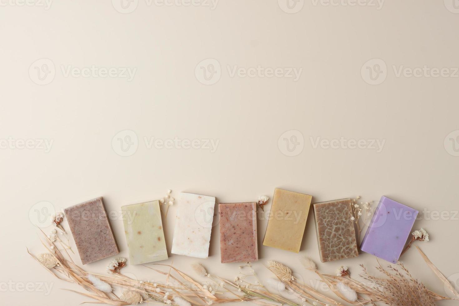 Soap and flower on beige background. Flat lay, copy space. photo