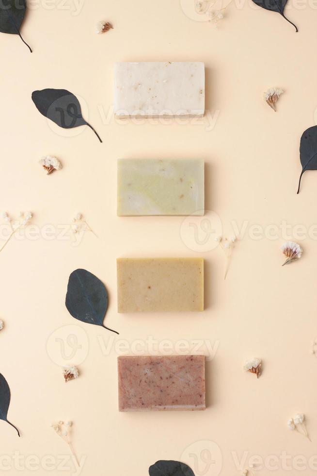 Soap with flowers on pastel beige background. Flat lay, copy space. photo