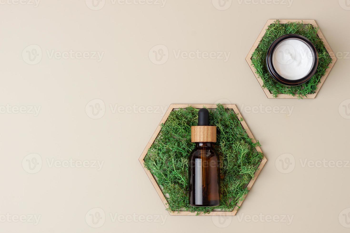 Cosmetic skin care products with a wooden hexagon and moss on pastel beige background. Flat lay, copy space photo