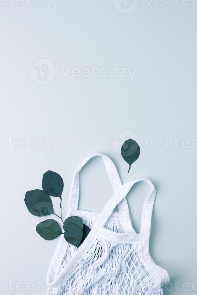 Zero waste, sustainable and eco-friendly lifestyle. Basket and eucalyptus on grey background. Flat lay, copy space photo