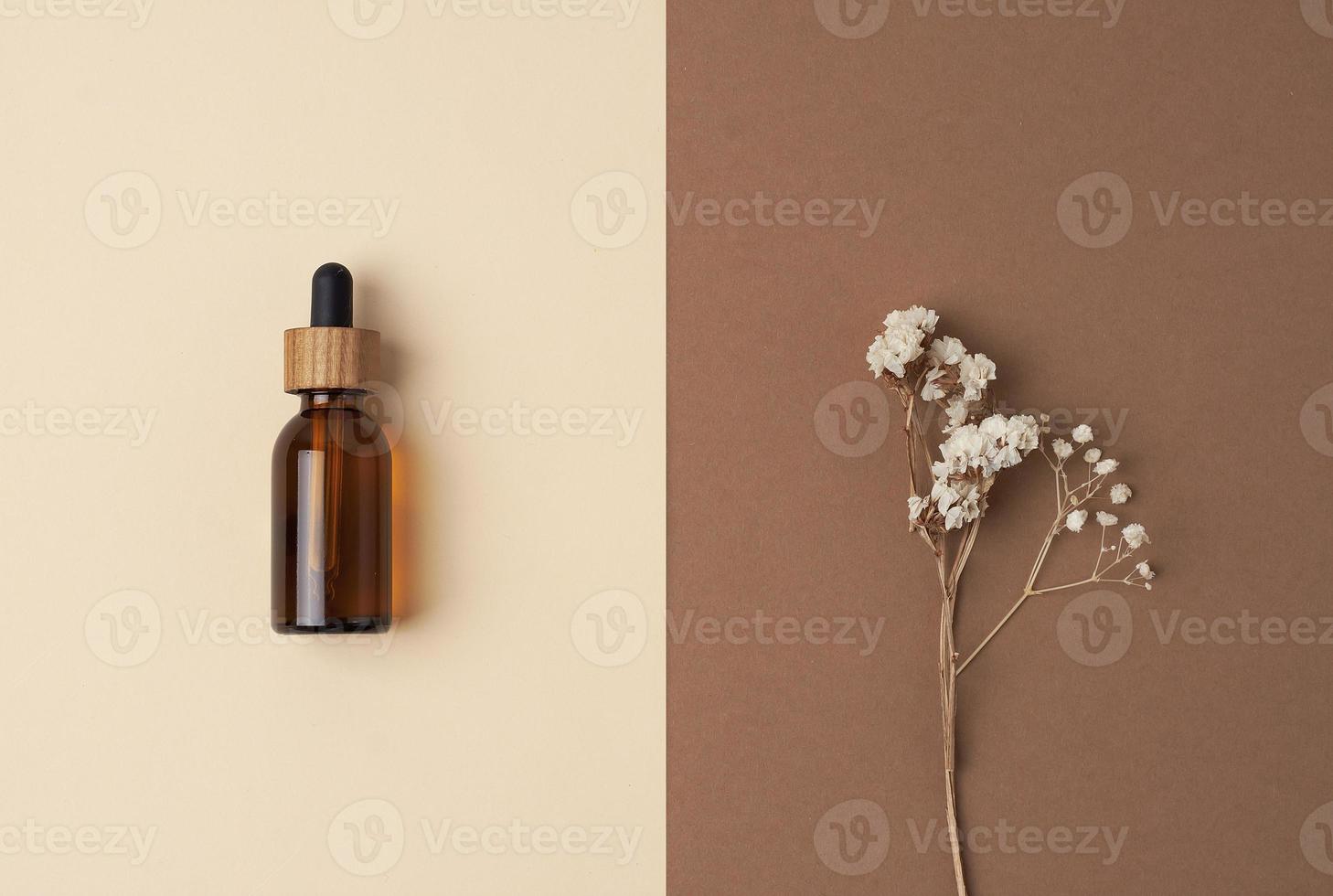 Minimal composition with cosmetic bottle and flowers on pastel beige background. Flat lay, copy space. photo