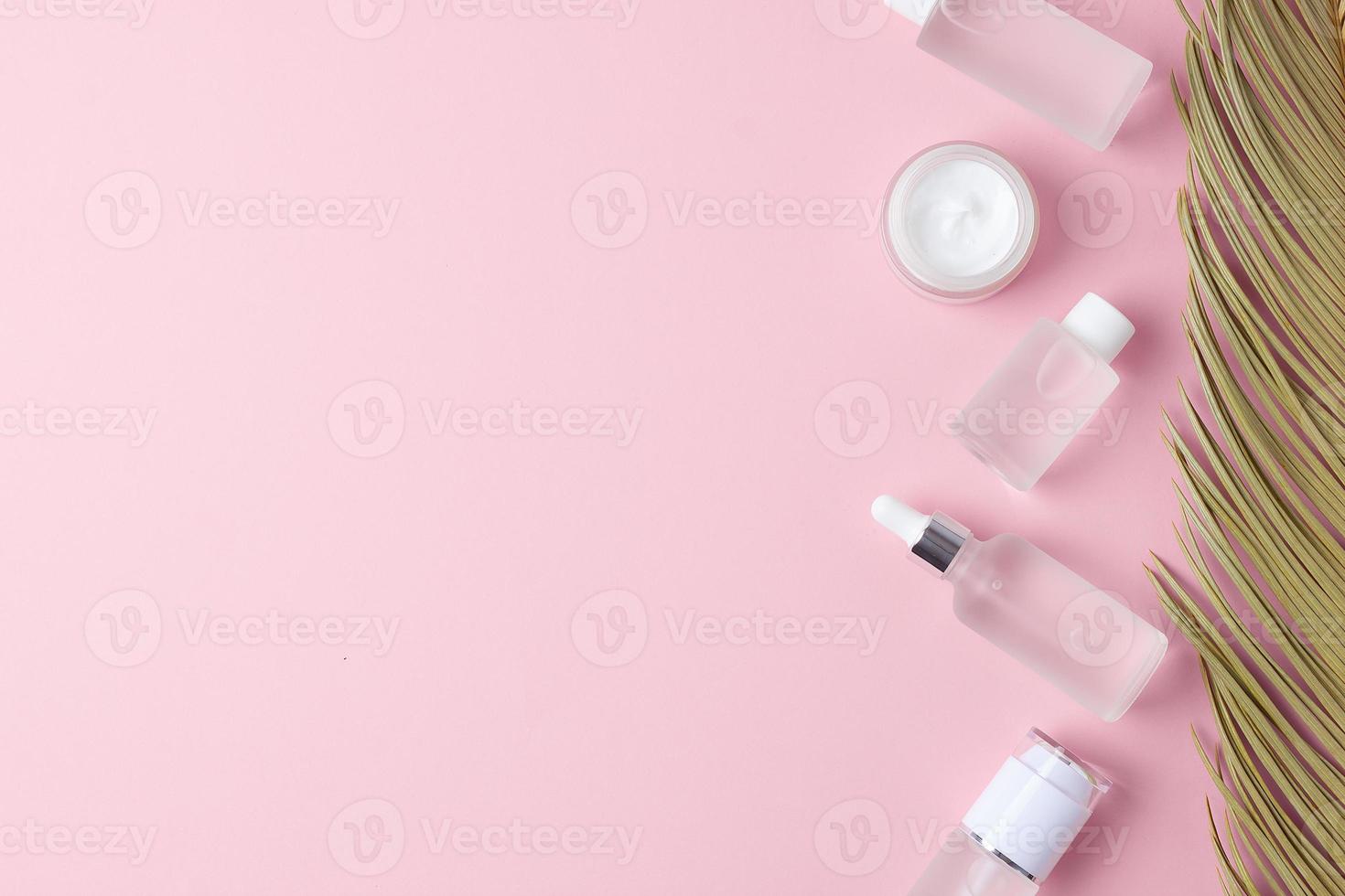 productos cosméticos para el cuidado de la piel con hoja de palma sobre fondo rosa. endecha plana, espacio de copia foto