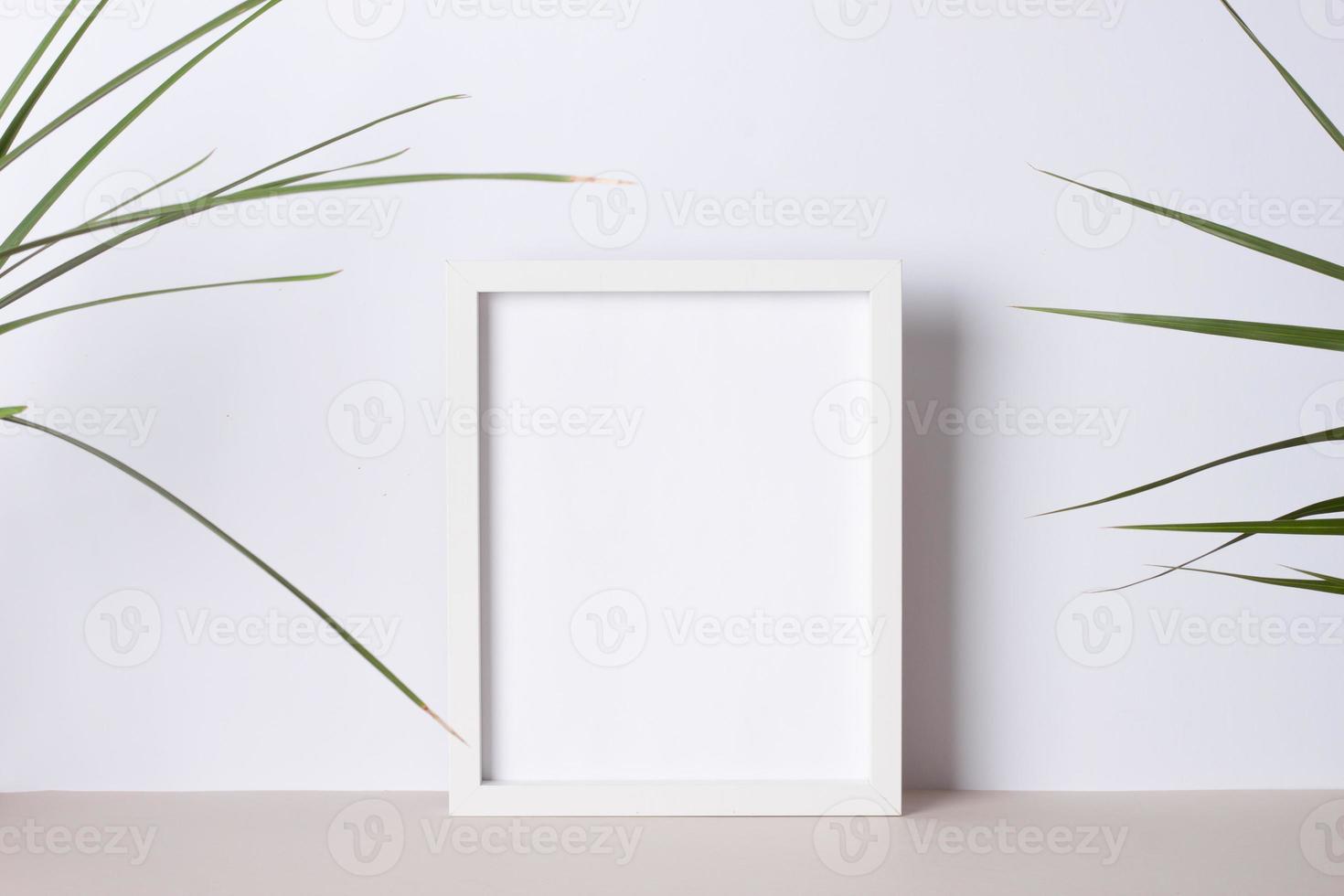 Home decoration with white mock up frame and palm leaf on grey. Artwork showcase. Close up, copy space photo