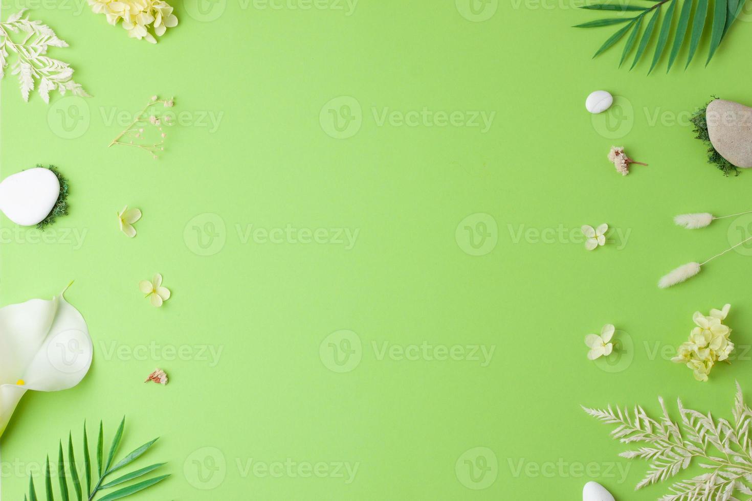 Cosmetic background with flowers, moss and stone on green. Flat lay, copy space photo