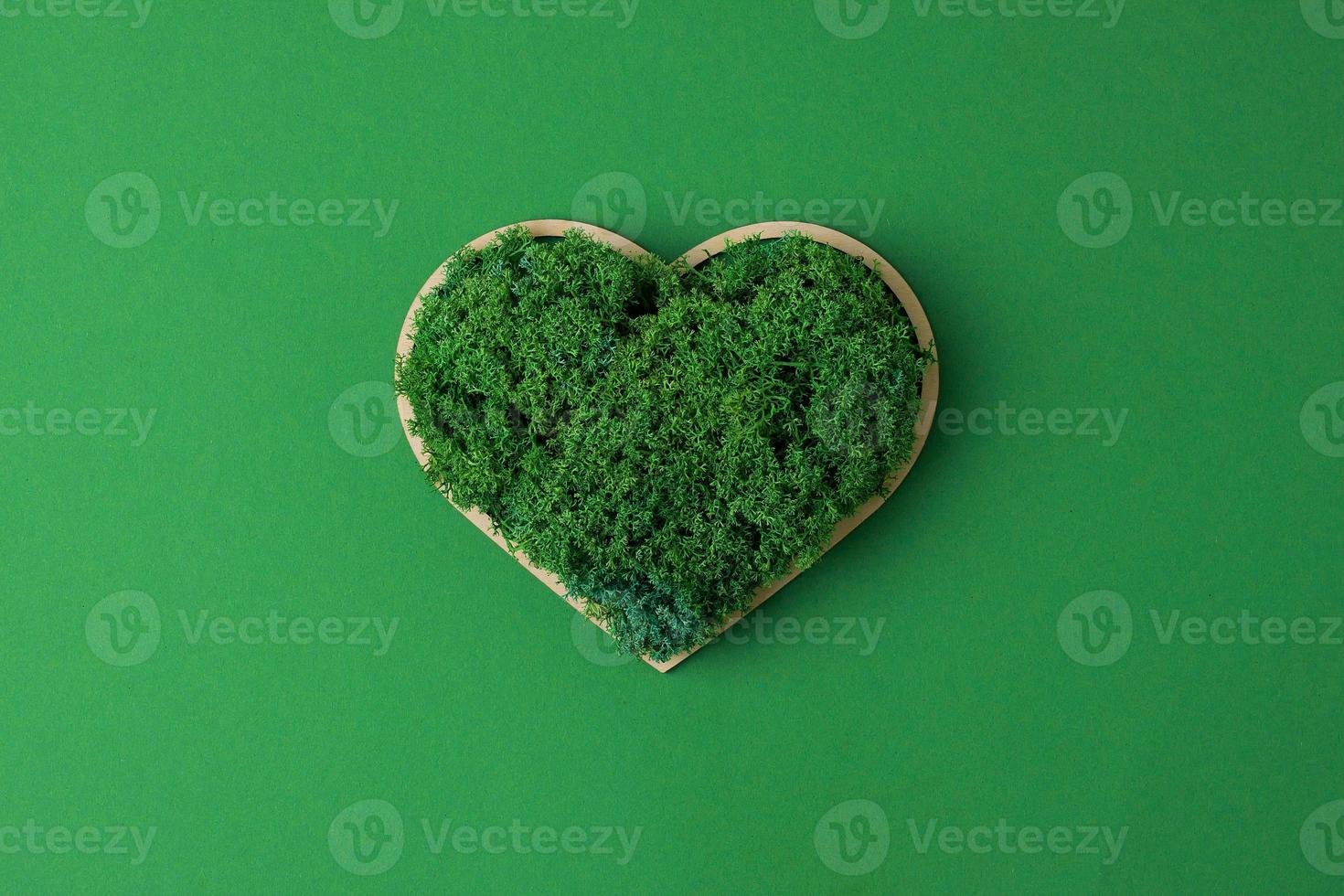 Cosmetic background with a wooden heart and moss on green. Flat lay, copy space photo