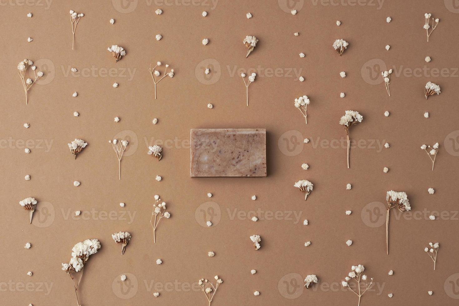 Soap and flower on brown background. Flat lay, copy space. photo