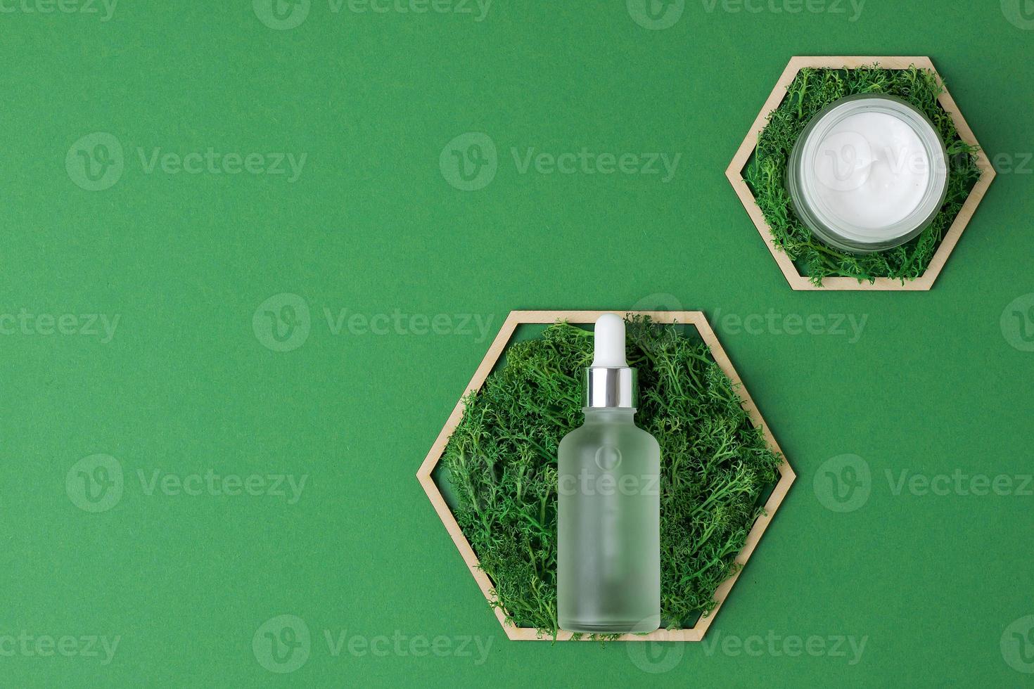 Cosmetic skin care products with a wooden hexagon and moss on green background. Flat lay, copy space photo