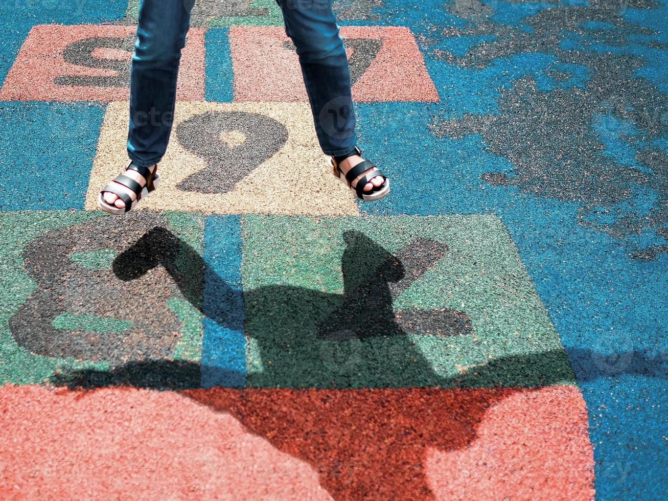 Low angle view of a girl playing the hopscotch in the playground photo