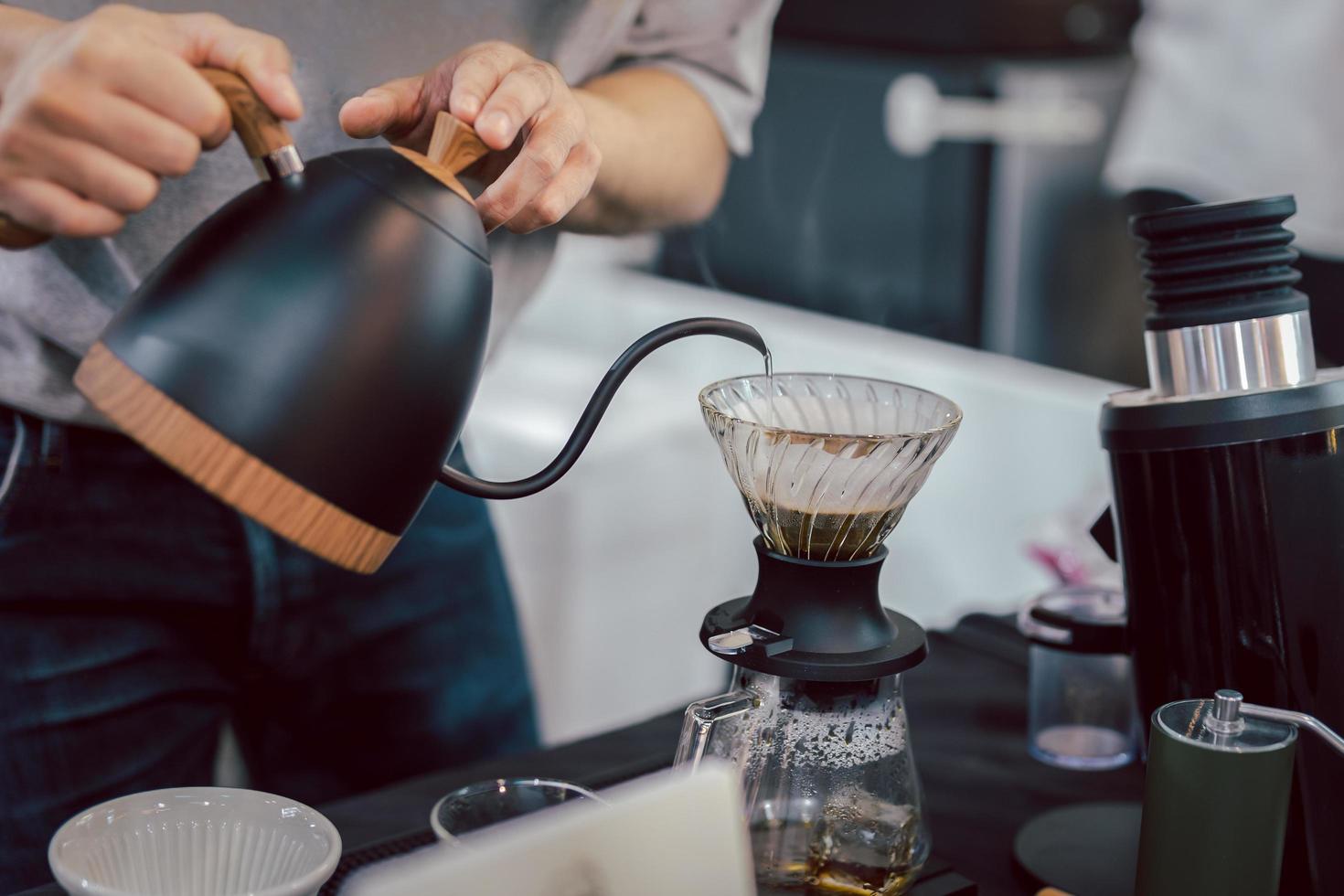 Barista pour hot water on rough brown bubbles coffee through drip filter. photo