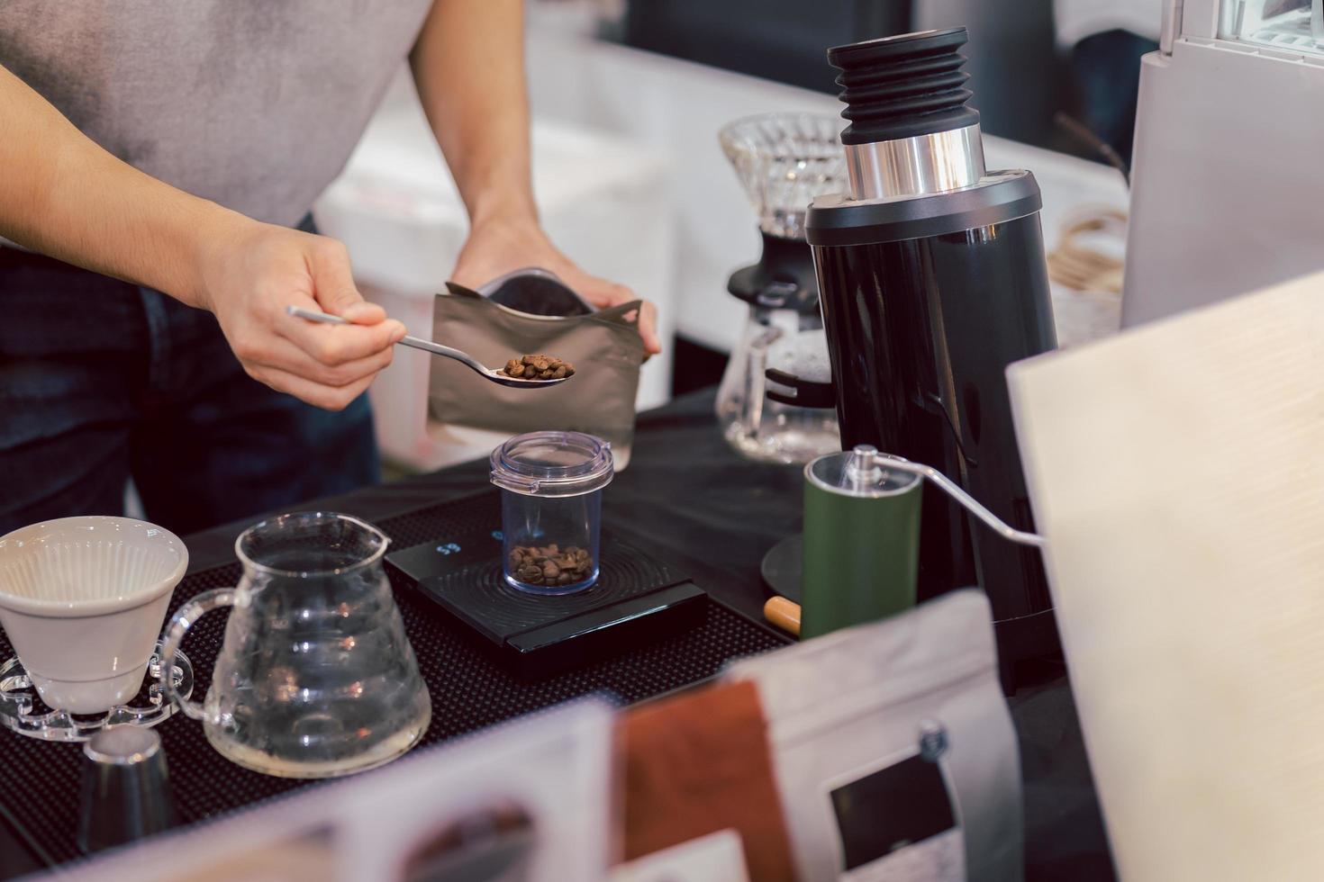 Barista meauring roasted coffee grains on a scale before brewing coffee. photo