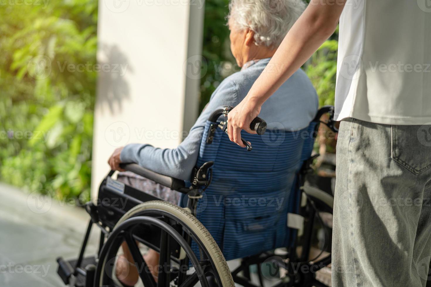 Caregiver help and care Asian senior or elderly old lady woman patient sitting on wheelchair to ramp in nursing hospital, healthy strong medical concept. photo