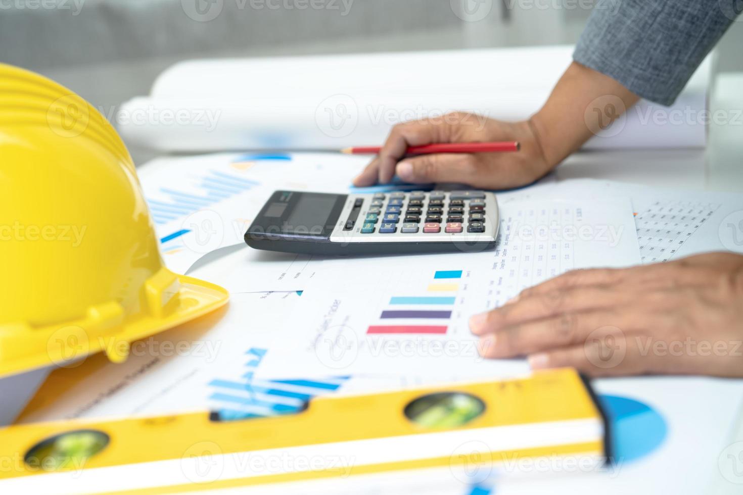 Asian engineer with architectural house plan project blueprint, graph and yellow helmet and engineering construction tools. photo