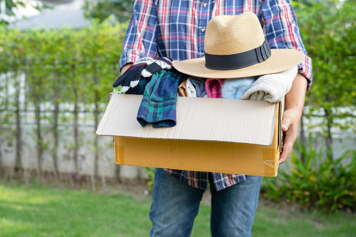 Holding clothing donation box with used clothes and hatl at home to support help for poor people in the world. photo